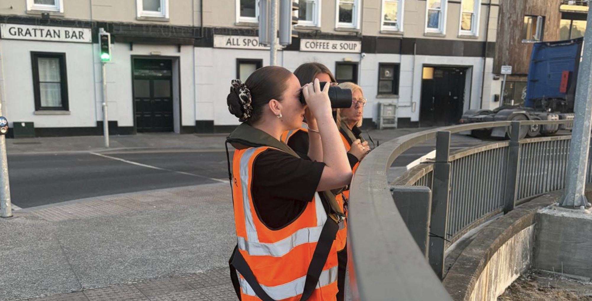 A volunteer scanning the river with binoculars on the quay