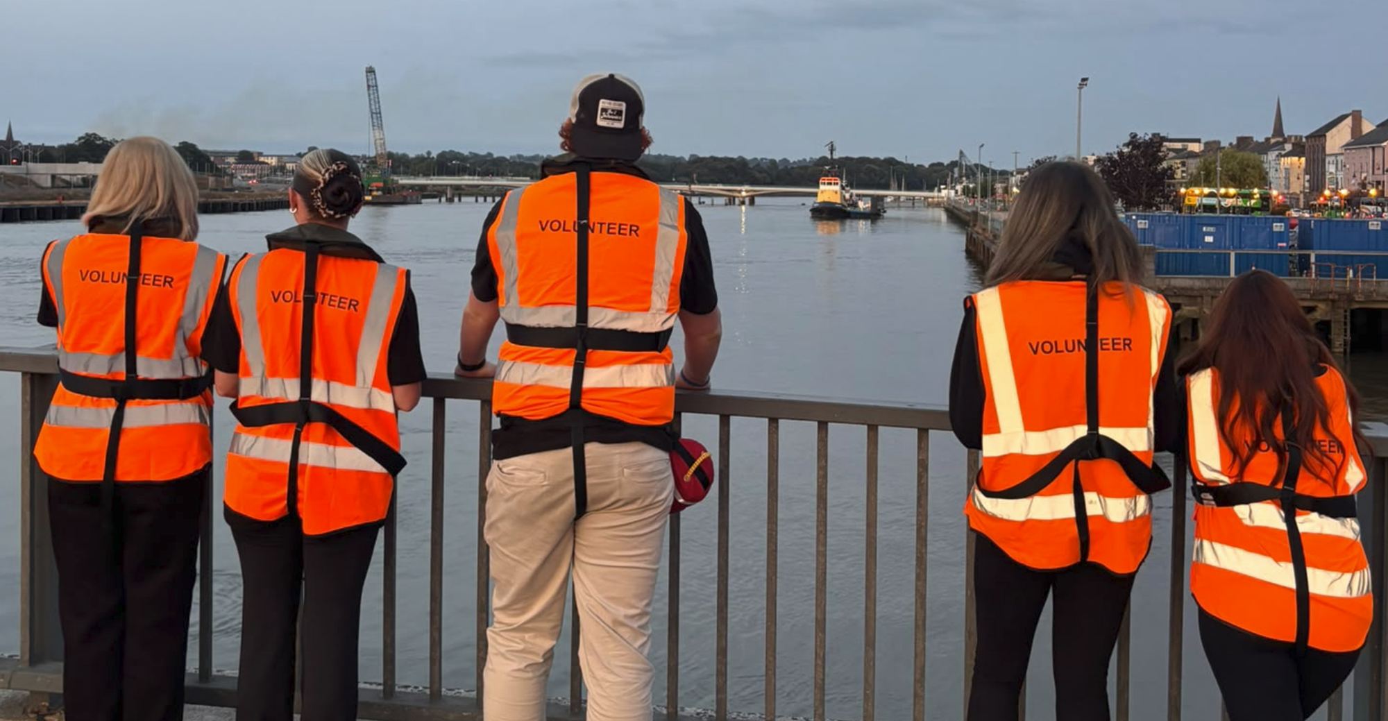 Five volunteers leaning on the bridge railing looking down the River Suir