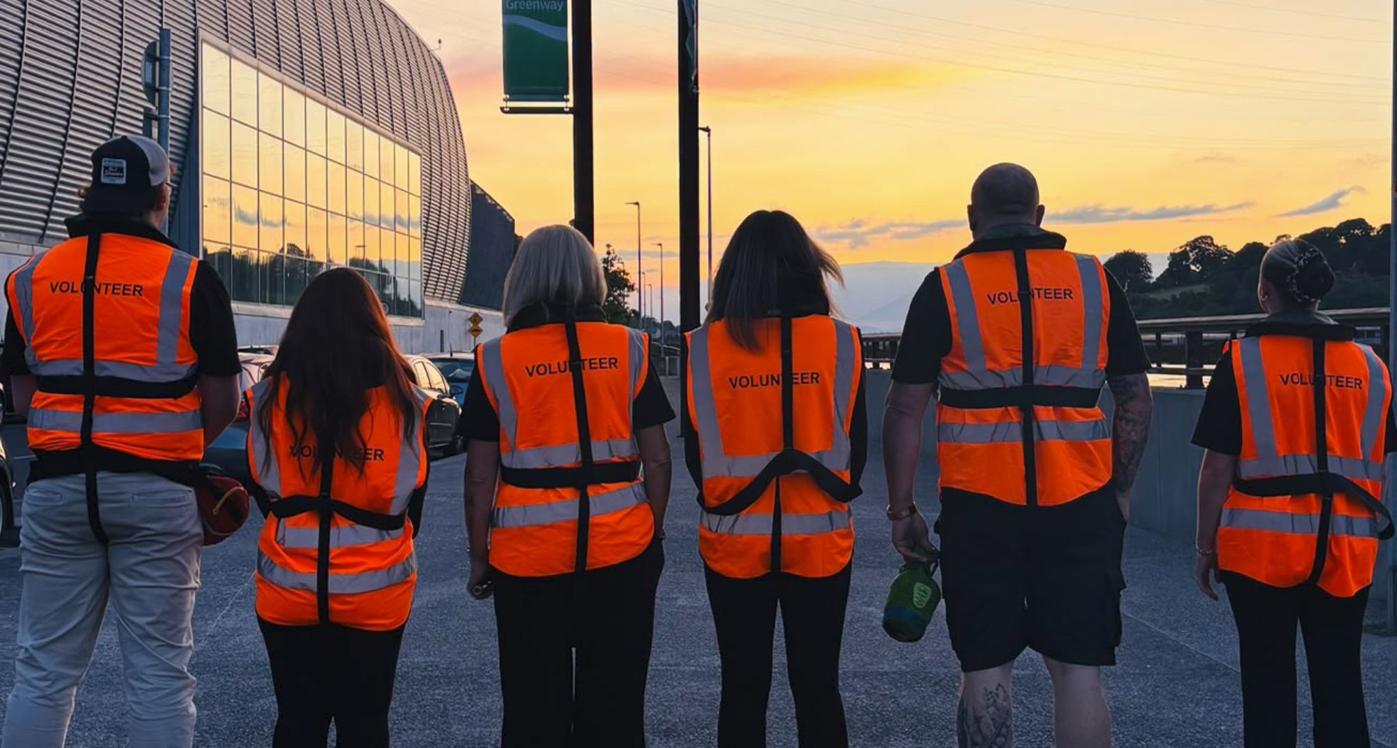 Six volunteers in hi-vis vests on the Greenway at sunset