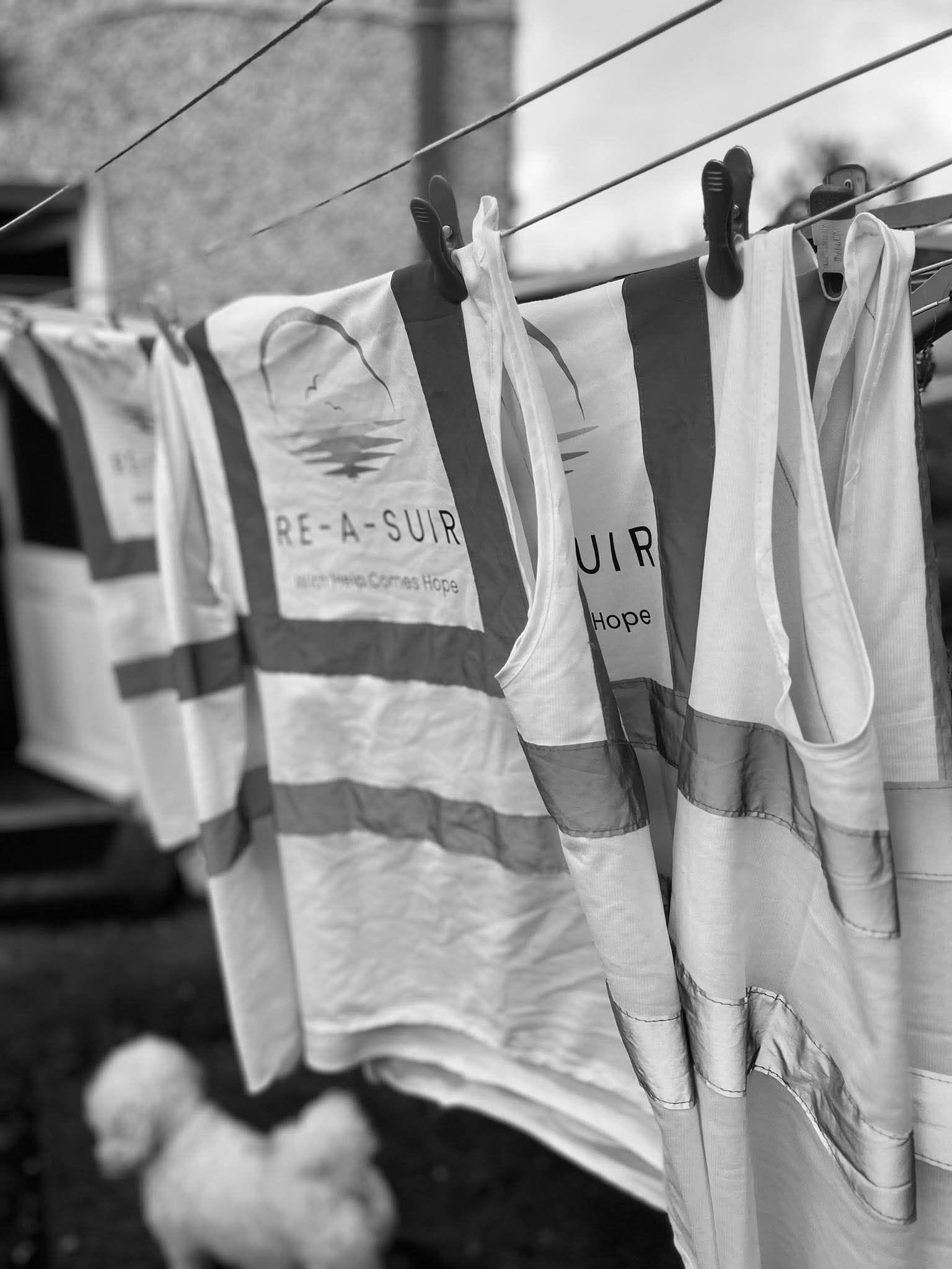 Branded Re-A-Suir hi-vis vests drying on a washing line, reading With Help Comes Hope